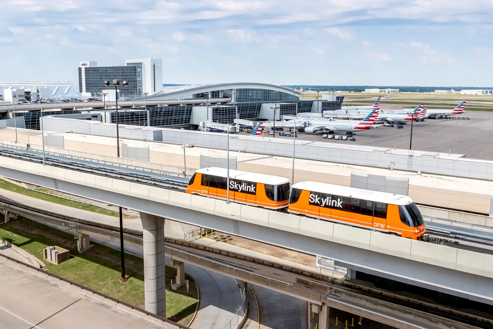 The DFW Skylink automated train traveling on the elevated track above the airport tarmac