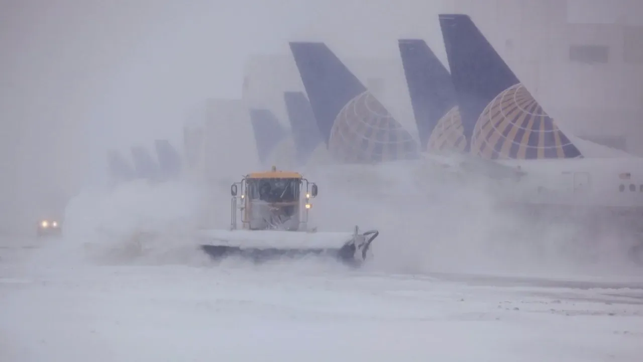A commercial airplane getting de-iced on the tarmac during a heavy winter snowstorm at Denver International Airport